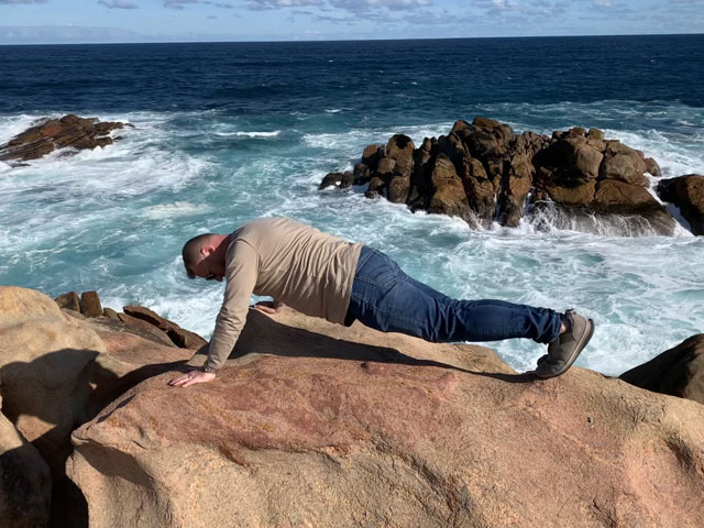 A person lying on a rock by the water   with medium confidence