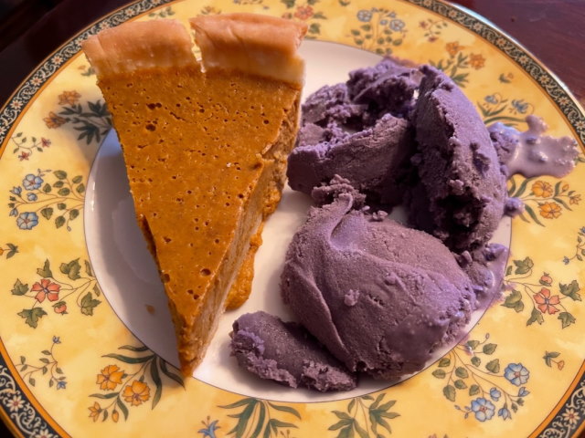 A slice of pumpkin pie and ube ice cream on a plate.