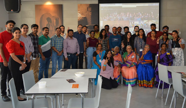 A large group of volunteers pose in front of a projector screen. 