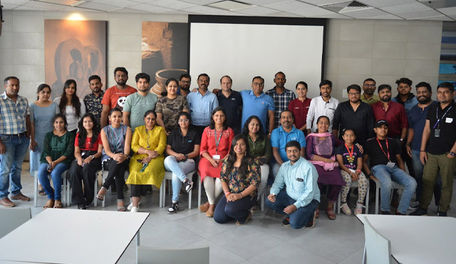 A large group of volunteers pose in front of a projector screen. 