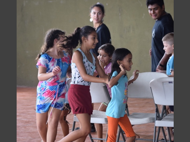 Children playing and running around chairs.