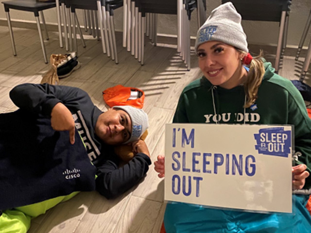 Jair and a colleague holding a sign that reads 'I'm sleeping out.'