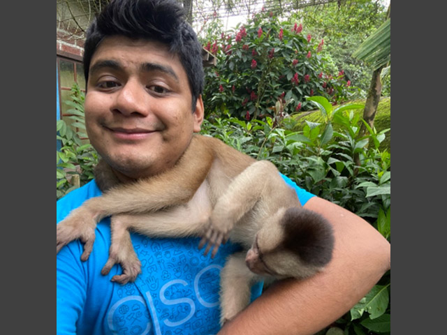 Jair with a small monkey climbing on him.