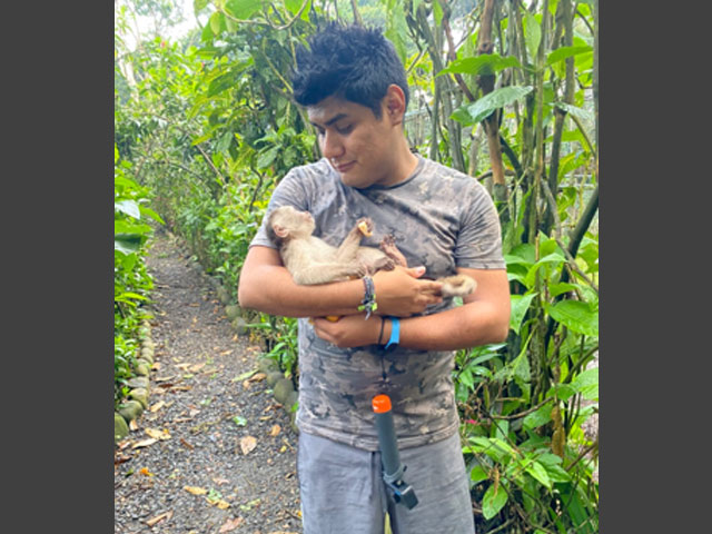 Jair holding a small monkey like a baby.