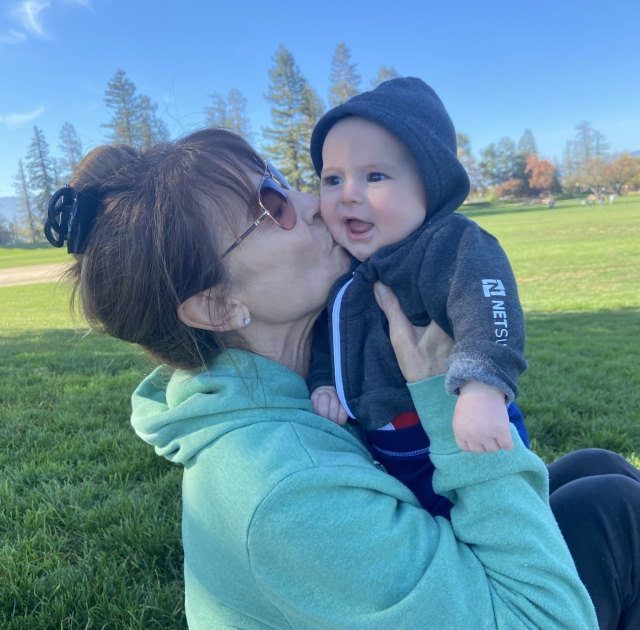 Cathryn holds her grandson Charlie and kisses him on the cheek.