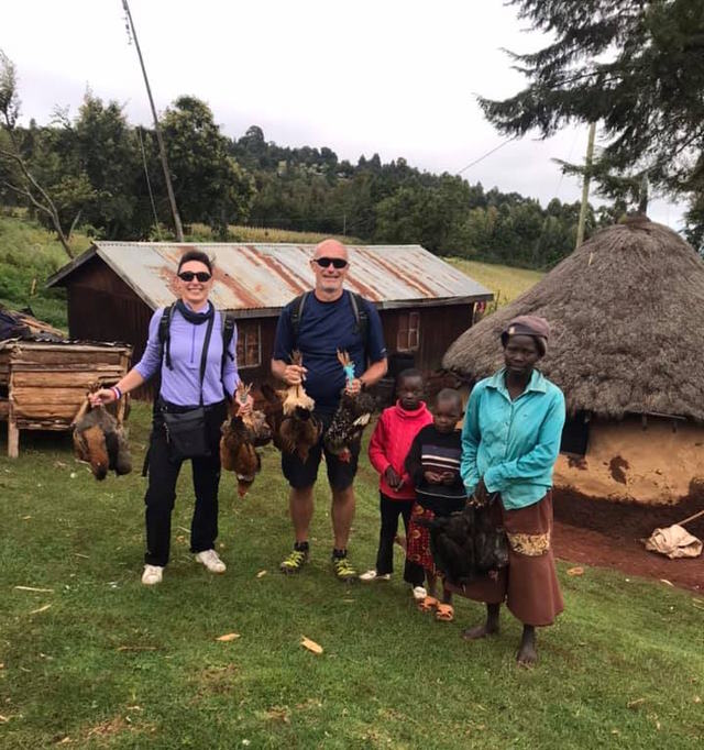 Laurent and his wife holding  chickens with their host family.