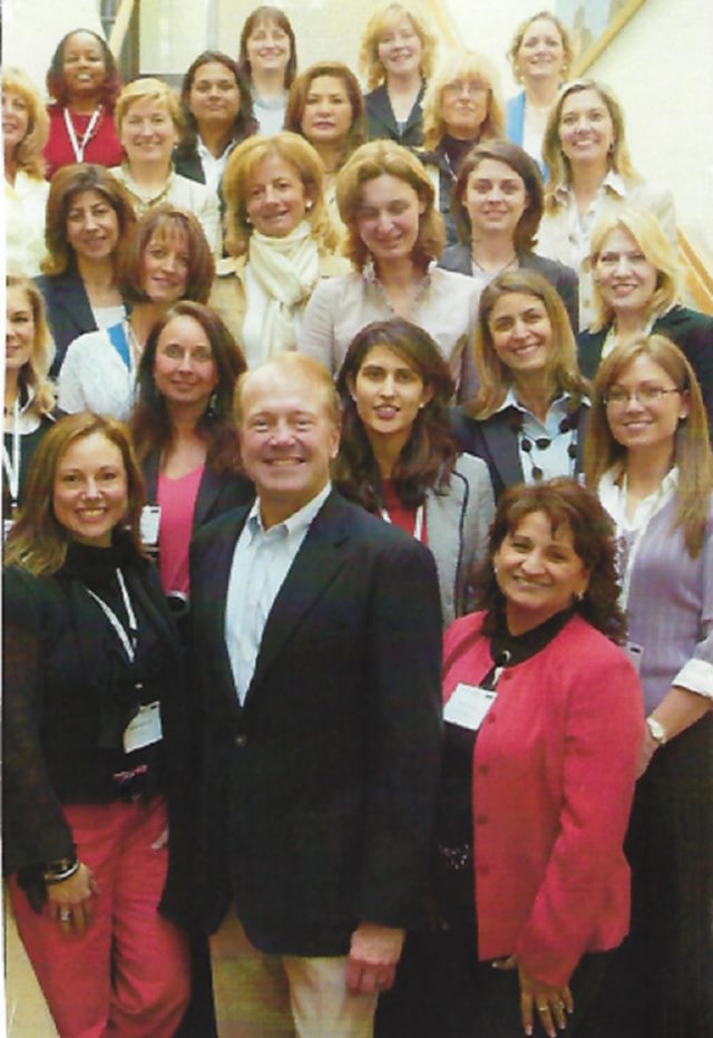 A group photo of Mona and other attendees with John Chambers.