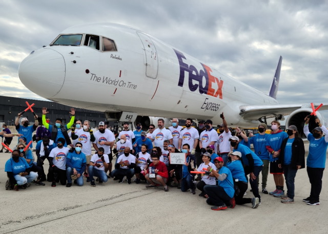 Large group of Cisco volunteers pose in front of an airplane they pulled.