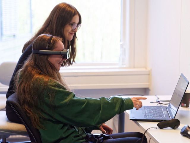 Two women in an office using a VR headset.