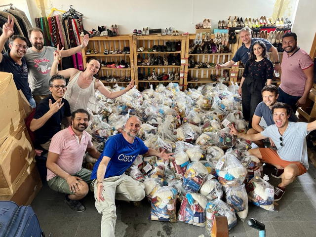 Layel’s team of volunteers  pose with a massive pile of complete food parcels.