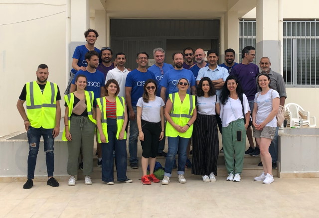 A large group of people in Cisco  shirts and neon vests gathered outside a building in Lebanon. 