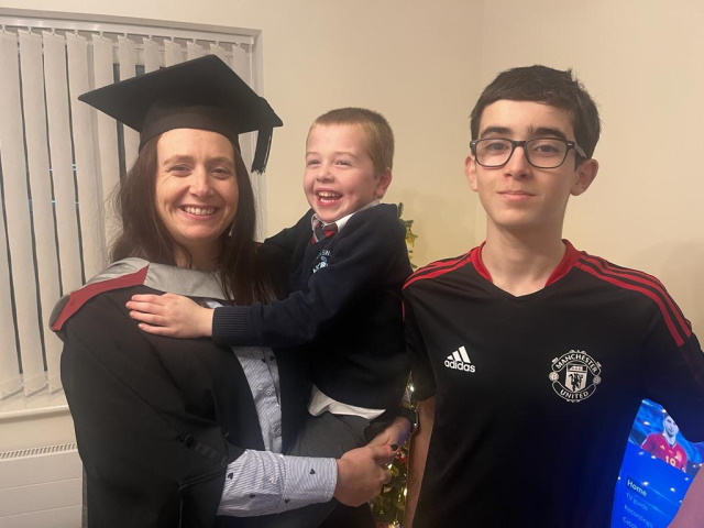 Emma with Tomas and Jack in a graduation gown