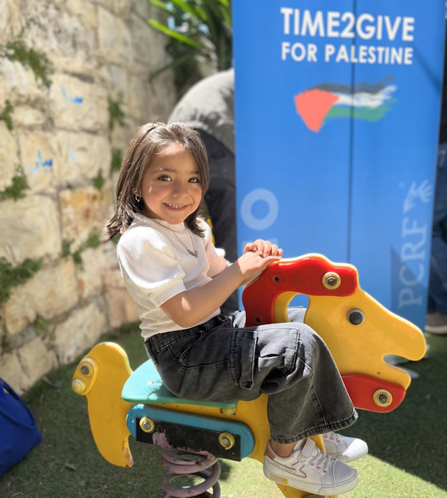 A young girl on a playground spring horse.