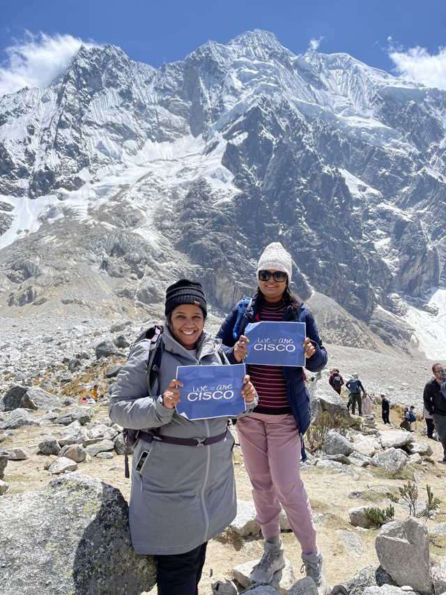 Suvidha and Madhu pose in front of dramatic snowy mountains.