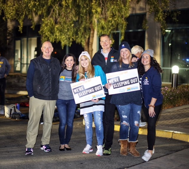 Rachael and a group of people dressed warmly standing outside a Cisco building at night.