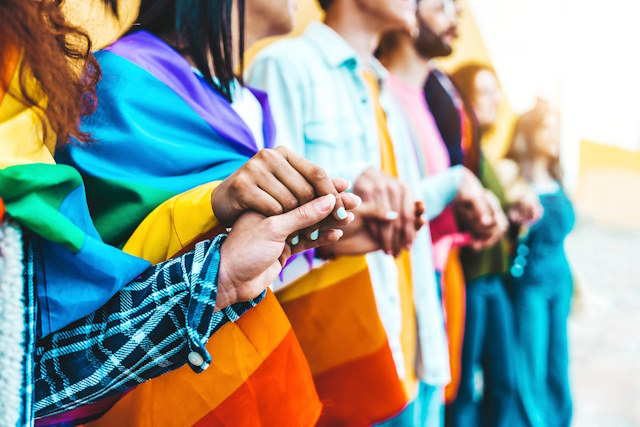 A group of people celebrating Pride and holding hands.