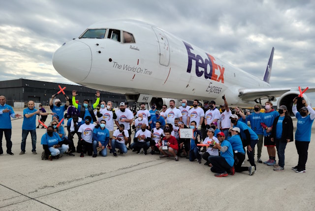 A large group of Cisco volunteers pose under the nose of a FedEx jet.