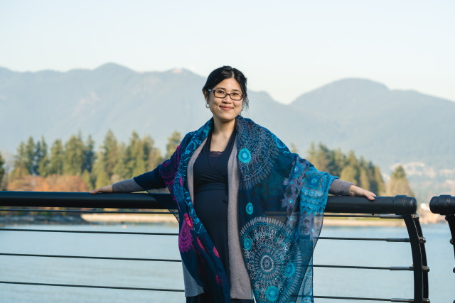 Annie Ying standing in the foreground with mountains, trees, and water behind her. 