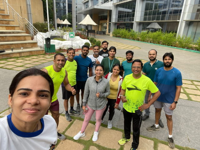 The  Cisco Runners Club in running gear pose for a photo outside among buildings.