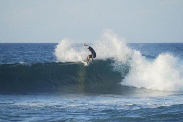 Pono taking a wave in his surfboard