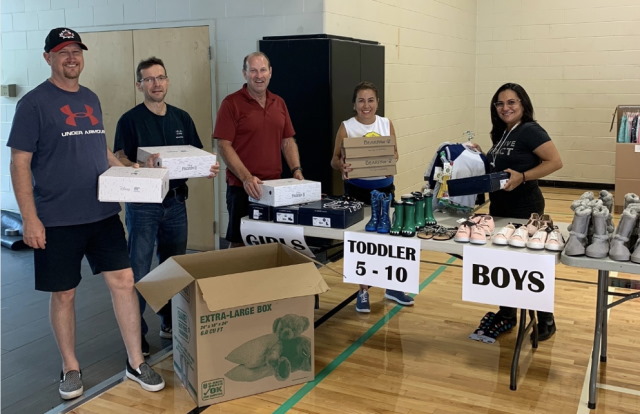 A small group of people standing among donated items at Kerr Street Mission. 