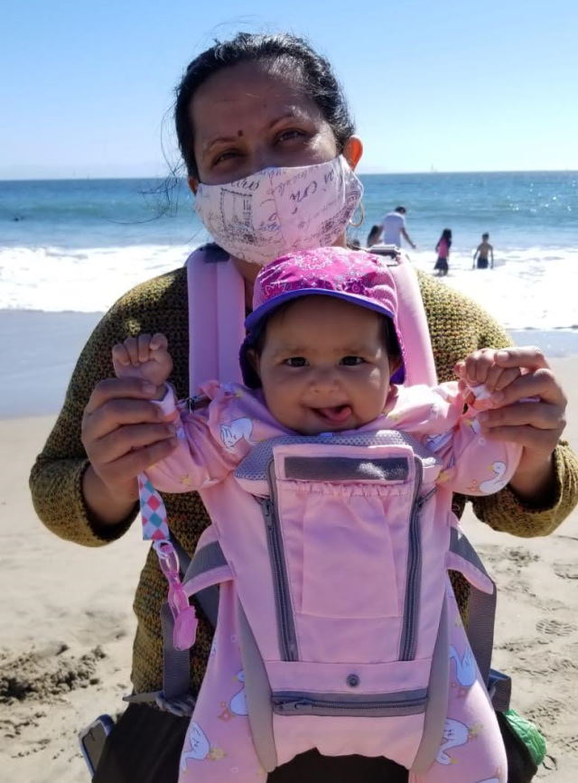 Hetal and her baby daughter Fiona  in a baby carrier at the beach.